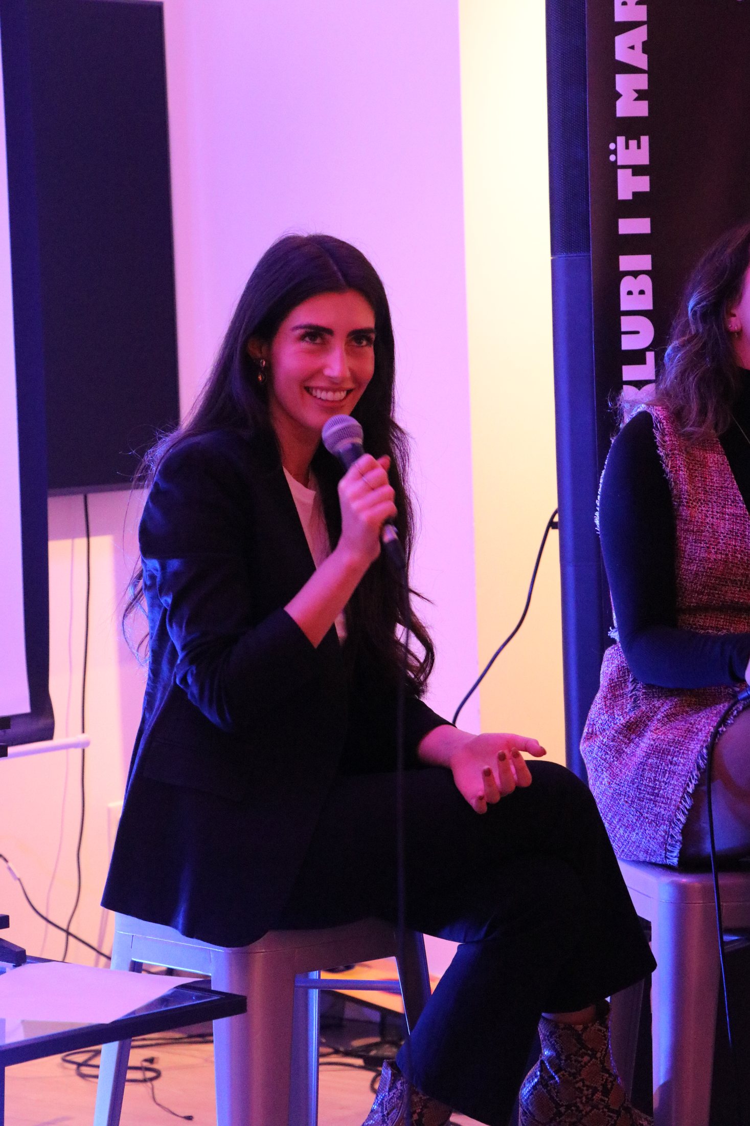 A woman speaking into a microphone during an Albanian Youth panel discussion